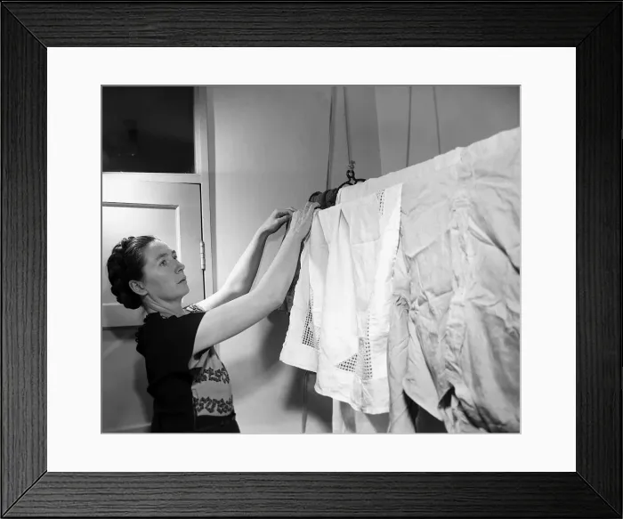 Framed Print : Housewives Washing Controversy A woman hangs up her laundry to dry in her North