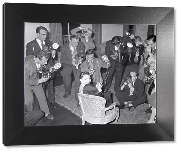 Actress Judy Garland at a press conference surronded by photographers taking