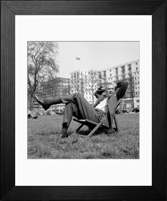 Framed Print : Gary Cooper sitting on a deck chair in London - April 1955 English flag in