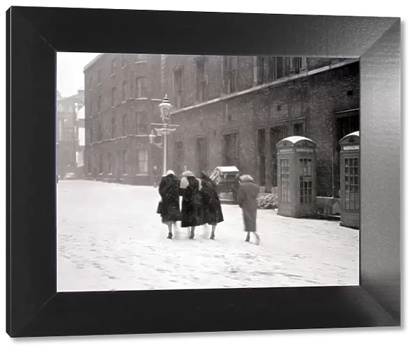 A group of women make their way up the street through the heavy snow past a row of