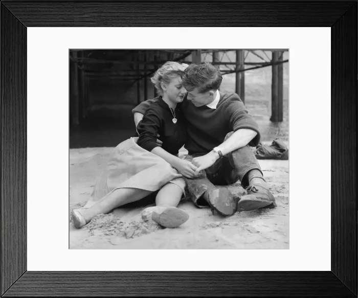 Framed Print : A young couple holding hands sitting on the beach Framed Print : A young couple holding hands sitting on the beach