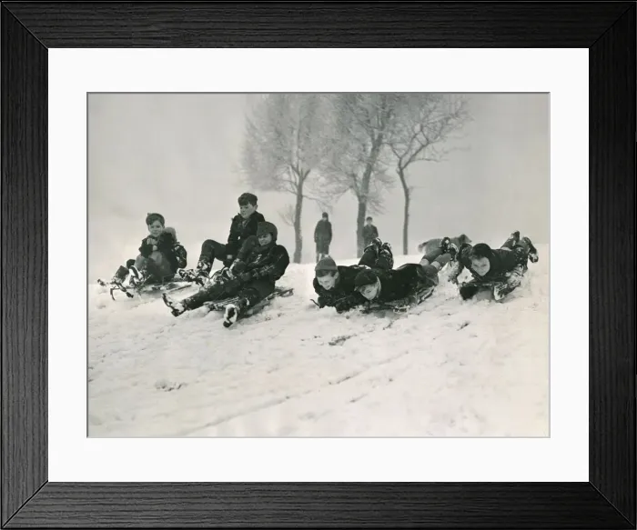 Framed Print : Children sledging down a hill in snow smiling and laughing after a havy snowfall Framed Print : Children sledging down a hill in snow smiling and laughing after a havy snowfall