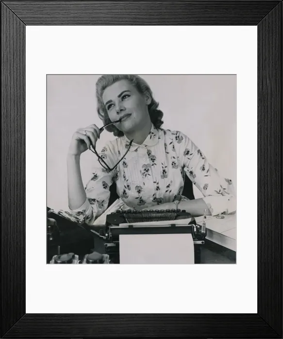 Framed Print : Office worker at typewriter chewing the end of her glasses July 1958 Framed Print : Office worker at typewriter chewing the end of her glasses July 1958