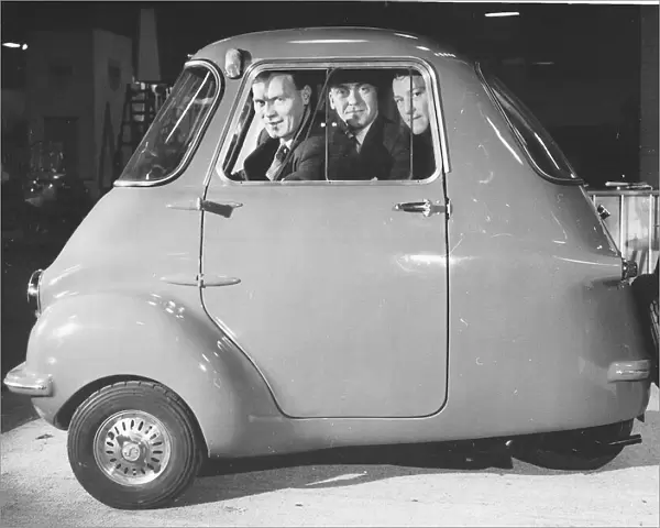 Three friends sit in a three wheeler Scootacar at the Earls Court Cycle and Motorshow