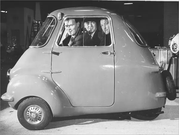 Three friends sit in a three wheeler Scootacar at the Earls Court Cycle and Motorshow