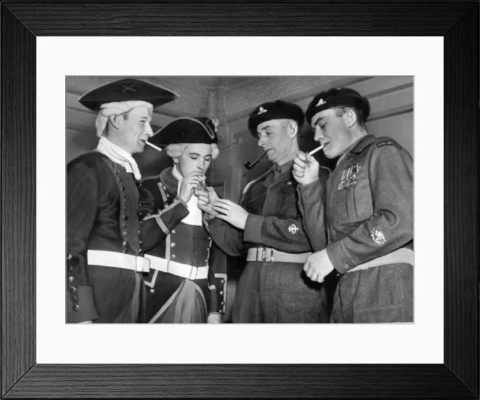 Framed Print : Dressed for battle, the two gunners from the past, share a light with todays soldiers in