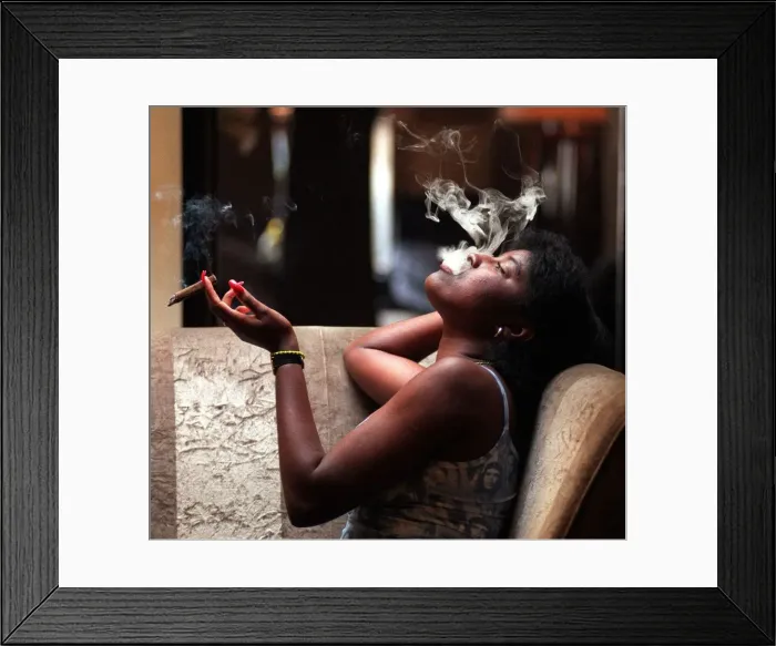 Framed Print : A woman sitting at a table smoking a cigar August 1998