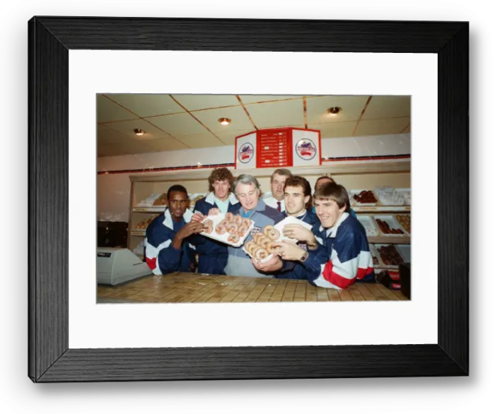 Framed Print : England manager Bobby Robson enjoying a selection of doughnuts with members of his Framed Print : England manager Bobby Robson enjoying a selection of doughnuts with members of his