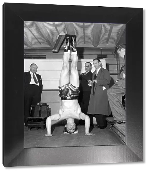 Cruiser weight boxer George walker doing a head stand at the weigh in November 1957