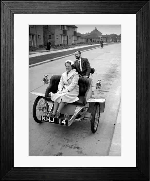 Framed Print : Laurence Mathew sitting in his veteran car with his wife driving behind May 1956