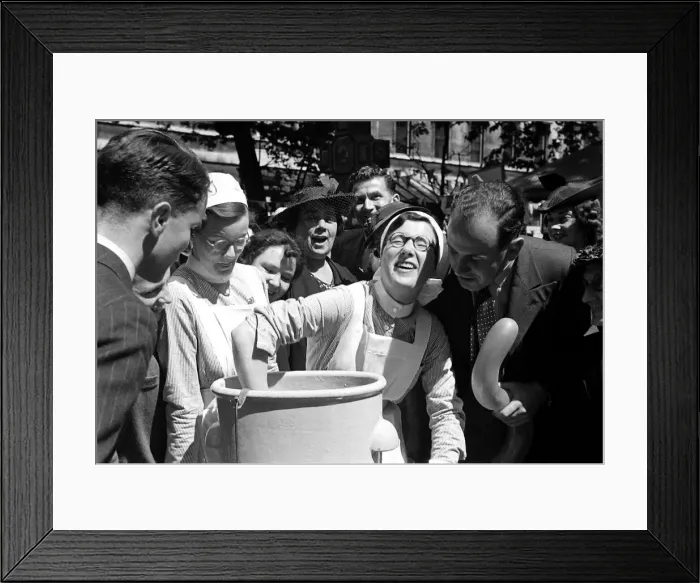 Framed Print : A nurse is watched as she dunks her hand into a bucket at Barts Fair April 1938
