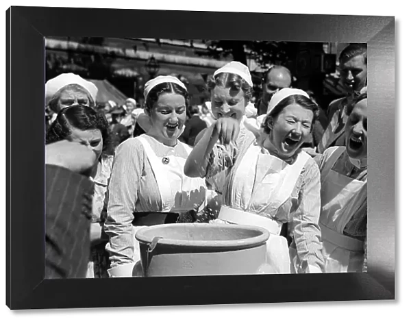 A group of nurses laugh as one has to dunk her hand into a bucket at Barts Fair