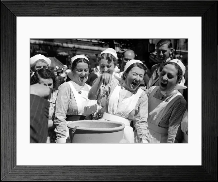 Framed Print : A group of nurses laugh as one has to dunk her hand into a bucket at Barts Fair Framed Print : A group of nurses laugh as one has to dunk her hand into a bucket at Barts Fair