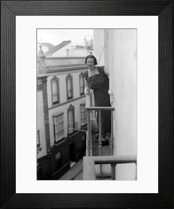 Framed Print : A local woman of Seville, Spain looks out over the town from the balcony of her town Framed Print : A local woman of Seville, Spain looks out over the town from the balcony of her town