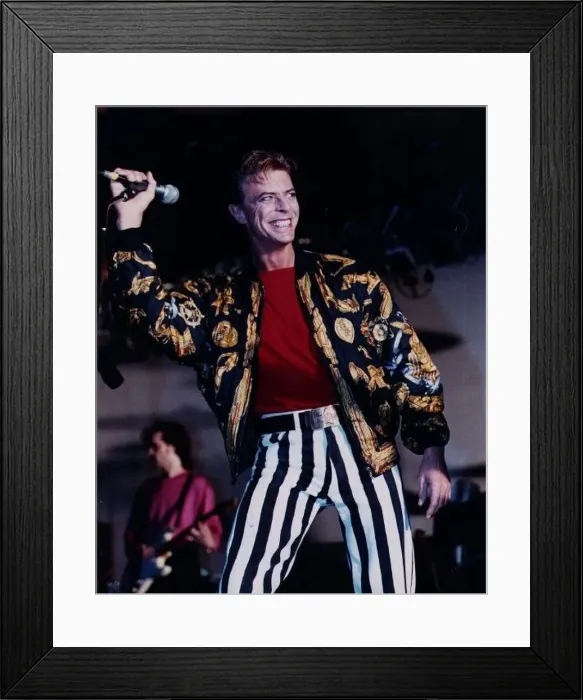 : David Bowie singer on stage mike in hand wearing black and white striped trousers red : David Bowie singer on stage mike in hand wearing black and white striped trousers red