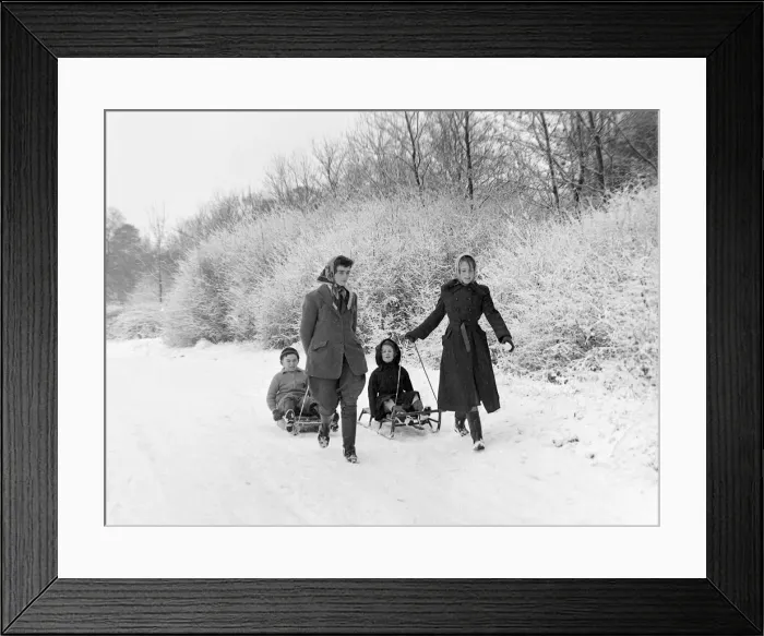 Framed Print : Children sledging in the snow in and around Hadley Wood Hertfordshire - two girls pulling