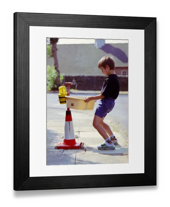 Framed Print : Sandpipes in Bradford - a boy fills a bucket full of water from an outside tap Framed Print : Sandpipes in Bradford - a boy fills a bucket full of water from an outside tap