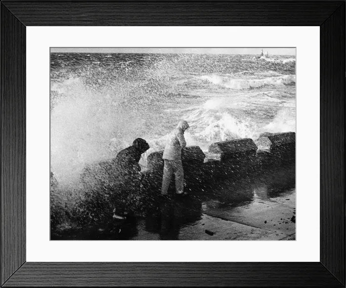 Framed Print : Two people in rain coats are soaked as a wave crashes over the sea front in Ayr Framed Print : Two people in rain coats are soaked as a wave crashes over the sea front in Ayr