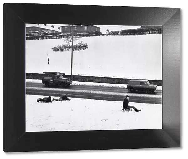 Youngsters sledge down the snow covered bank stopping only feet off the busy Newcastle