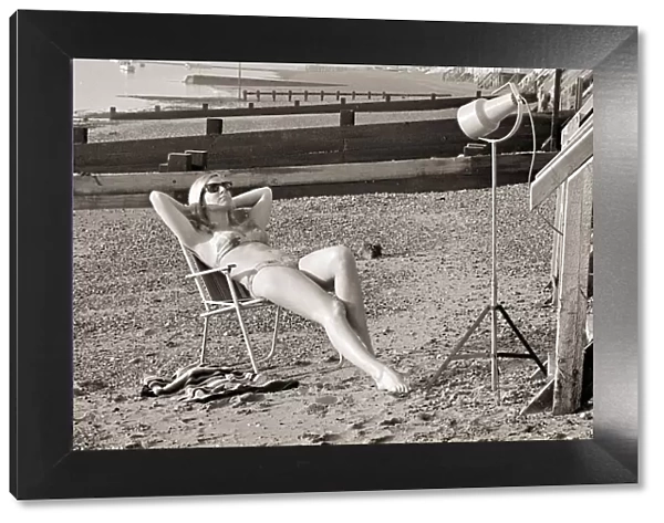 A model sunbathing under a UV lamp on the beach at Cleethorpes November 1967