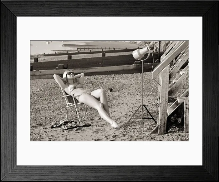 Framed Print : A model sunbathing under a UV lamp on the beach at Cleethorpes November 1967