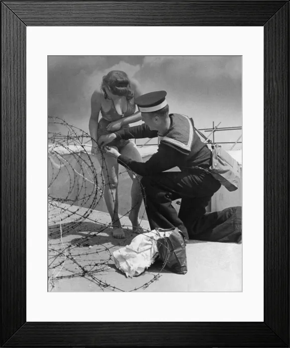 Framed Print : A sailor lends a hand when a female holidaymaker becomes entangled in barbed wire Framed Print : A sailor lends a hand when a female holidaymaker becomes entangled in barbed wire