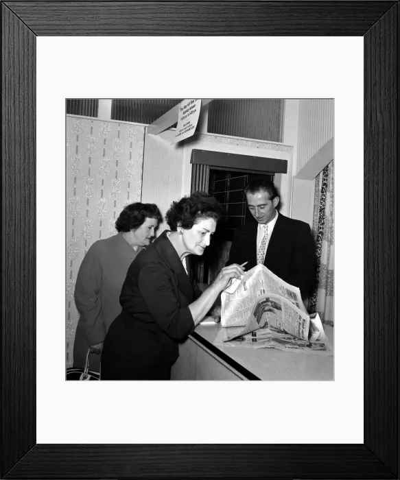 Framed Print : A woman punter studying the form guide before placing a bet in a betting shop