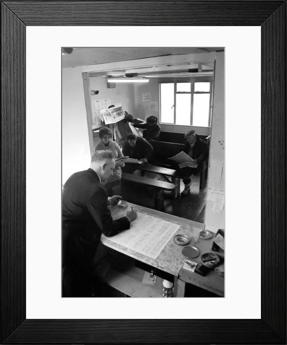 Framed Print : Mr Benniston, owner of Macs betting shop in Danesmoor near Chesterfield at work as