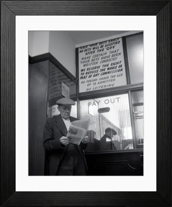 Framed Print : An elderly man studies the form guide inside A E Fane and Co betting shop in Islington Framed Print : An elderly man studies the form guide inside A E Fane and Co betting shop in Islington