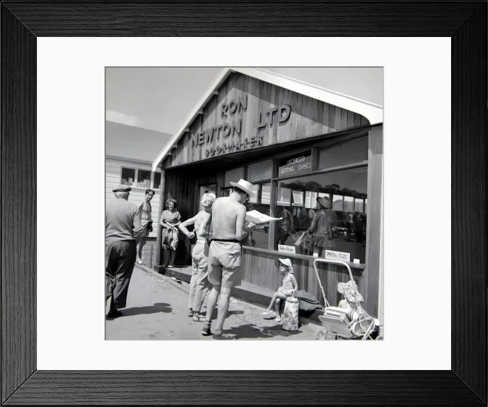 Framed Print : Holidaymakers study the form guide at a betting shop in the form of a wooden chalet Framed Print : Holidaymakers study the form guide at a betting shop in the form of a wooden chalet