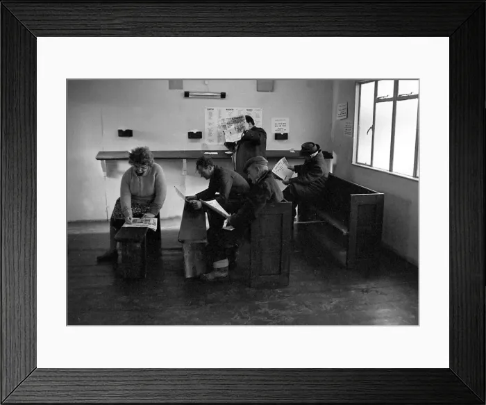 Framed Print : Punters seated on church pews as they study the guide before placing a bet at Mac