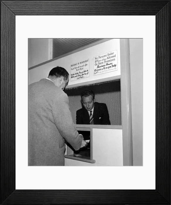 Framed Print : A bookmaker accepting a bet from a punter at Eric Barbers betting shop in Old Trafford Framed Print : A bookmaker accepting a bet from a punter at Eric Barbers betting shop in Old Trafford