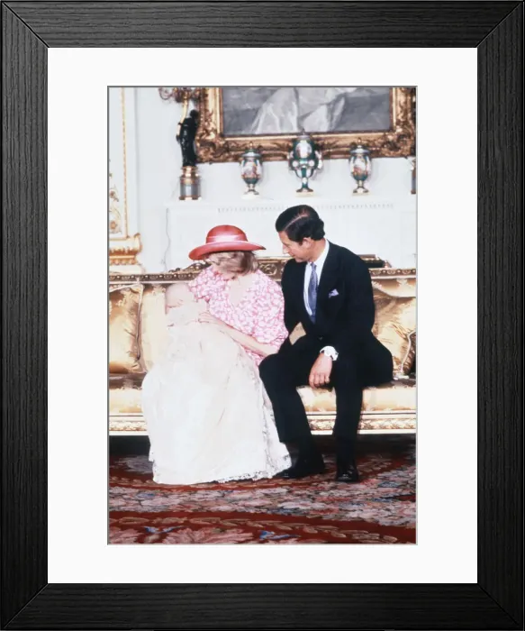 Framed Print : Princess Diana, watched by husband prince Charles, holds her son Prince William in her Framed Print : Princess Diana, watched by husband prince Charles, holds her son Prince William in her