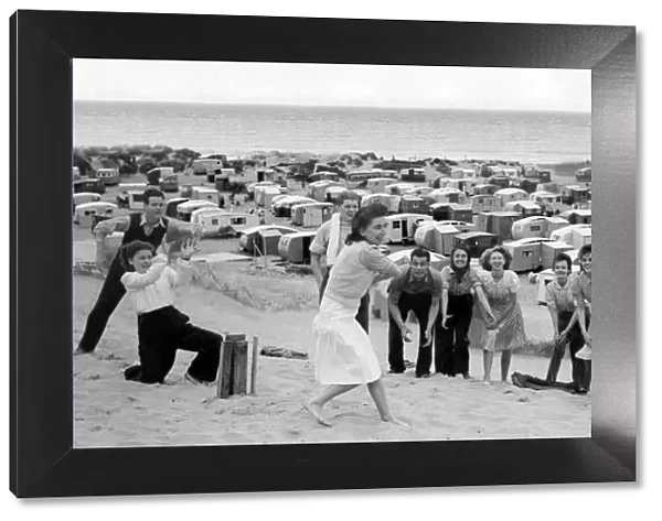 Men and women play a game of cricket on the sand beach. Holidays in Britain