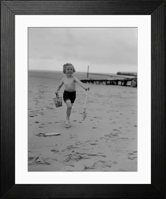Framed Print : A small girl runs on the beach carrying her bucket and spade enjoying the May Bank Framed Print : A small girl runs on the beach carrying her bucket and spade enjoying the May Bank