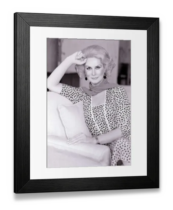 Framed Print : Model April Ashley sitting on a sofa wearing a print dress with one hand at her head May Framed Print : Model April Ashley sitting on a sofa wearing a print dress with one hand at her head May