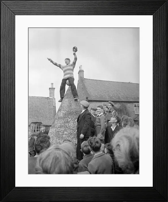Framed Print : Hallaton Barrel Kicking man perched atop of a stone structure circa 1946