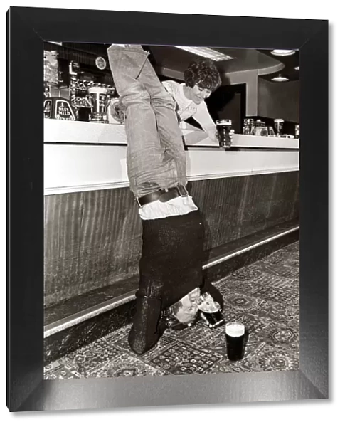 Drinking - A man doing a headstand in his local pub drinking his pint of beer upside down