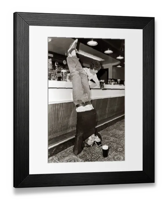 Framed Print : Drinking - A man doing a headstand in his local pub drinking his pint of beer upside down