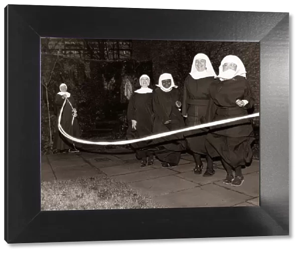Fun loving nuns enjoying a game of skipping behind the walls of their convent