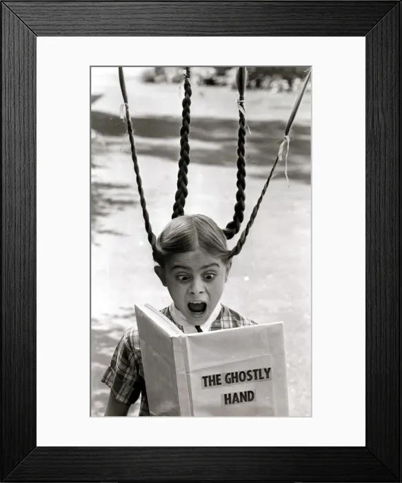 Framed Print : A girls pigtails stand on end in terror as she reads a scary ghost story Framed Print : A girls pigtails stand on end in terror as she reads a scary ghost story