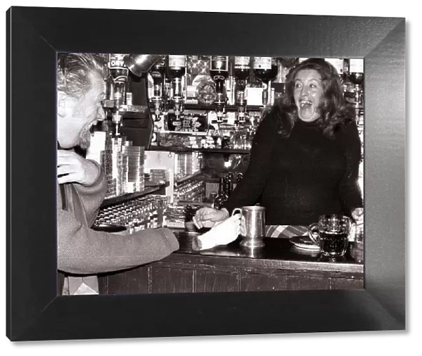 A barmaid at the Red Lion Pub in Kings Langley, Hertfordshire laughing after customer