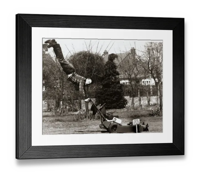 Framed Print : A man mowing his lawn with doing a hand stand on the handles of an electrical lawn mower Framed Print : A man mowing his lawn with doing a hand stand on the handles of an electrical lawn mower