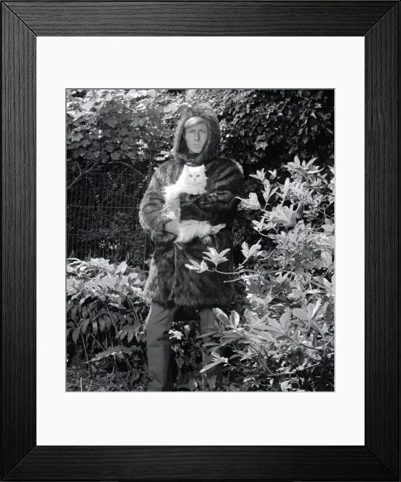 Framed Print : Ted Dawson modelling a fake fur coat with a hood for men while holding a white furry cat