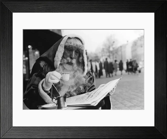 Framed Print : Father Christmas sitting outside a cafe in Paris, reading the newspaper Framed Print : Father Christmas sitting outside a cafe in Paris, reading the newspaper