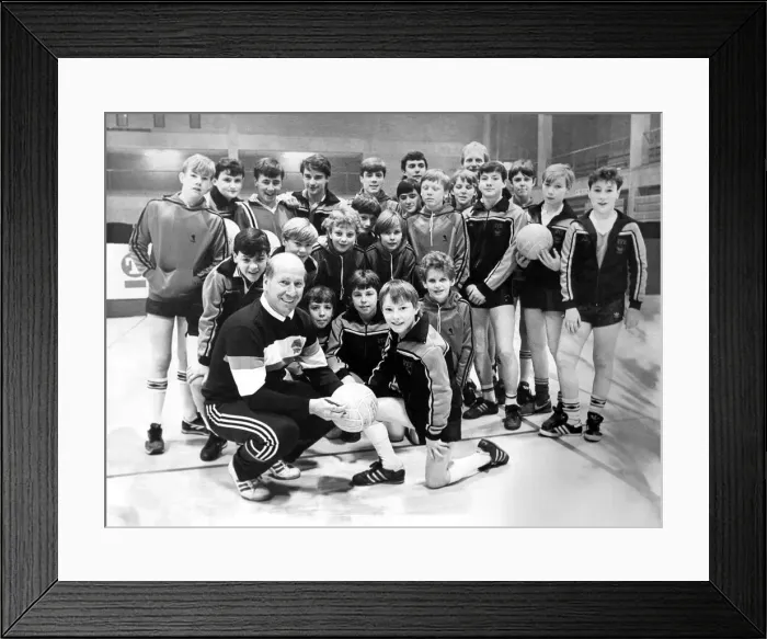 Framed Print : Bobby Charlton signs a football for 12 year old Christopher Milburn during a coaching Framed Print : Bobby Charlton signs a football for 12 year old Christopher Milburn during a coaching
