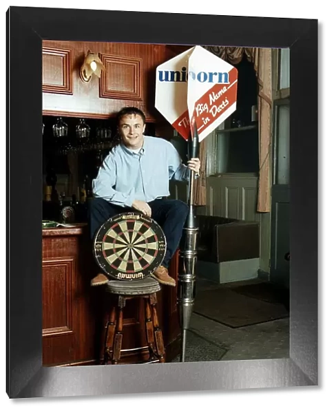 Chelsea and England footballer Dennis Wise poses in a public house with a dartboard