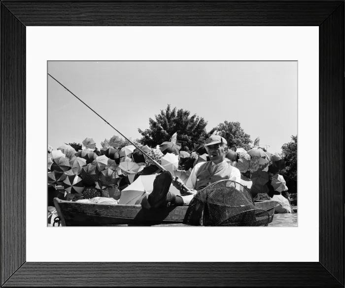 Framed Print : Joe Carver, owner of an umbrella making business, sitting in a fishing boat smoking a Framed Print : Joe Carver, owner of an umbrella making business, sitting in a fishing boat smoking a