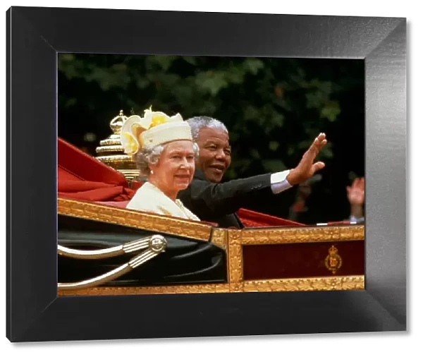 Nelson mandela waves from the carriage as he sits beside Her Majesty Queen Elizabeth II