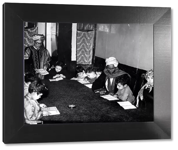 In a small room a group of children are learning the alphabet of Arabia with the Koran as